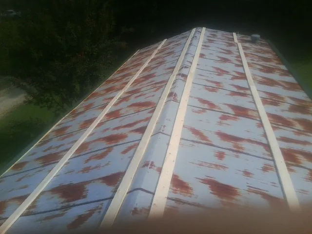 Rusted metal roof panels with new wood purlins before replacement — Storm Damage Roof Repair in Clyde Park by Roofing Brothers