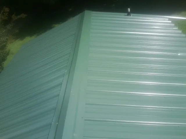 New green metal panels meeting at the ridge of a roof — Flat Roof Repair work by our crew in Clyde Park