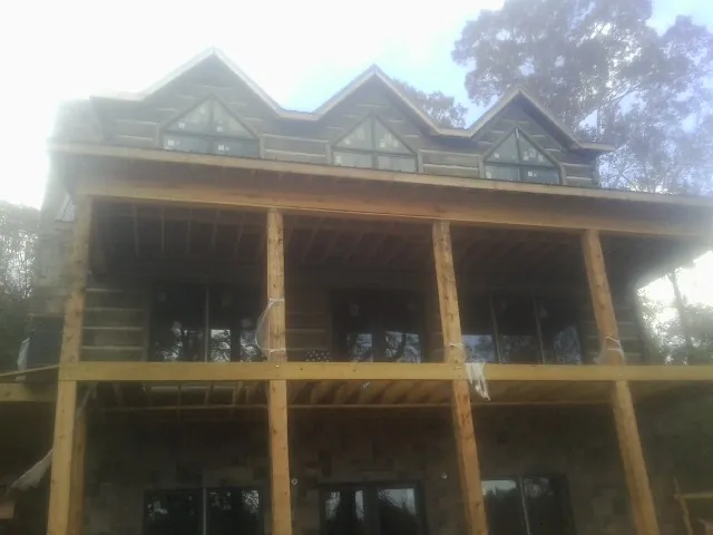 Dormers and porch framing on a large log home under construction — Roof Coating work by our crew in Clyde Park