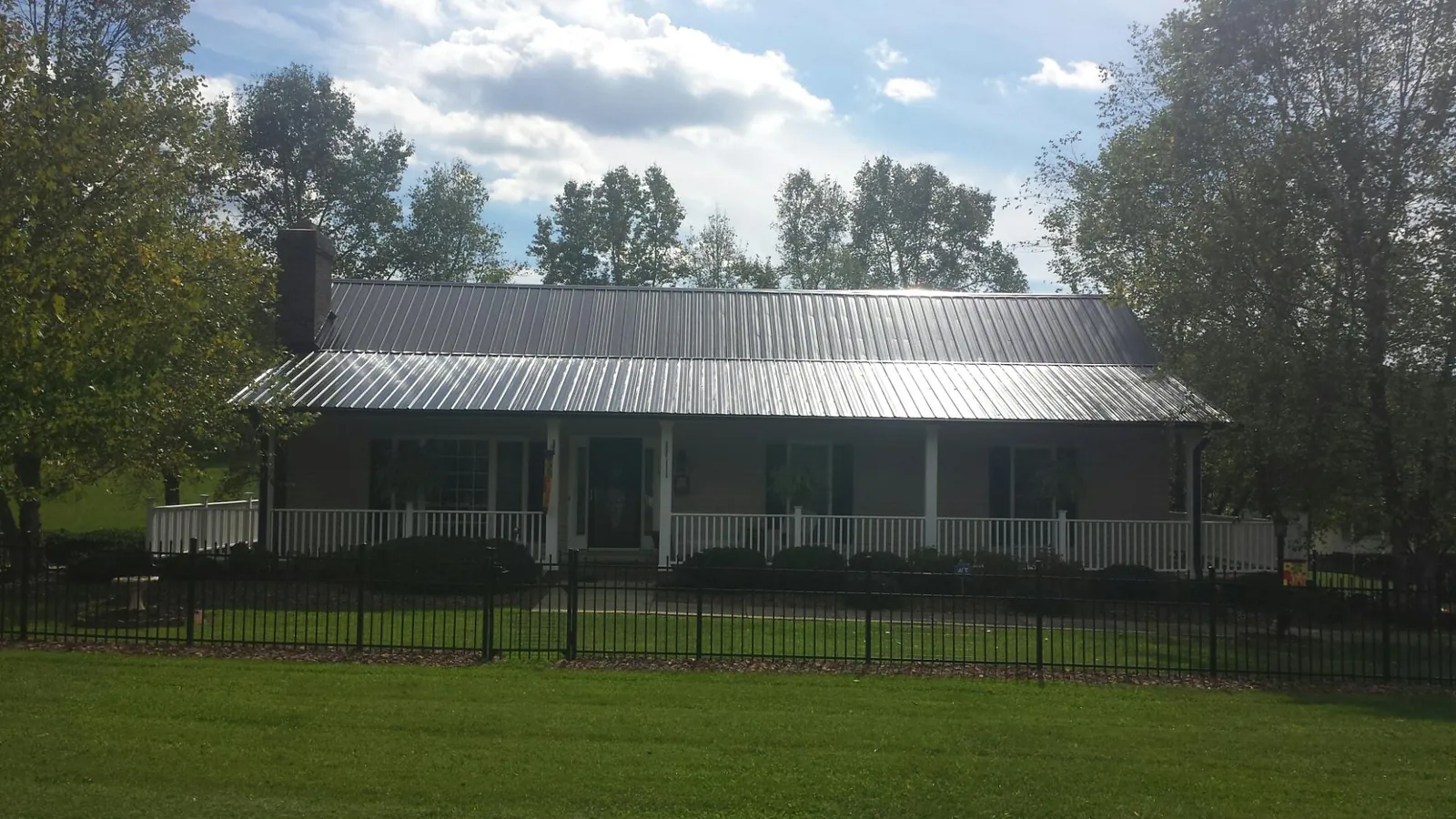 Gray metal roof on a brick ranch with a full width front porch — Gutter Guard Installation work by our crew in Clyde Park