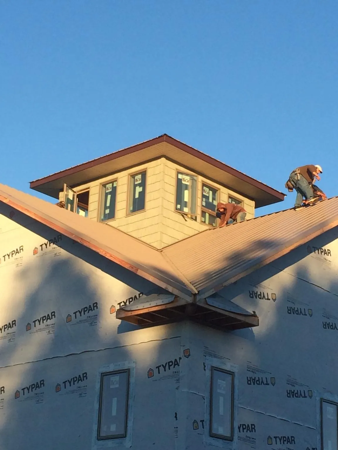 Roofers working around a rooftop cupola on a new metal roof at sunset — Roof Waterproofing in Clyde Park by Roofing Brothers